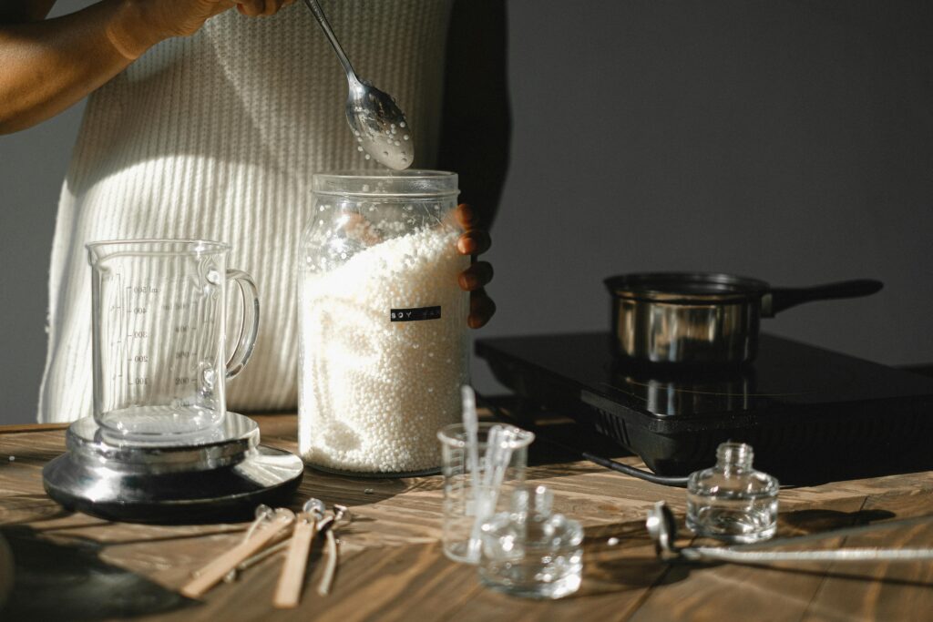 A woman preparing soy wax pellets for DIY candle making in a studio setting.