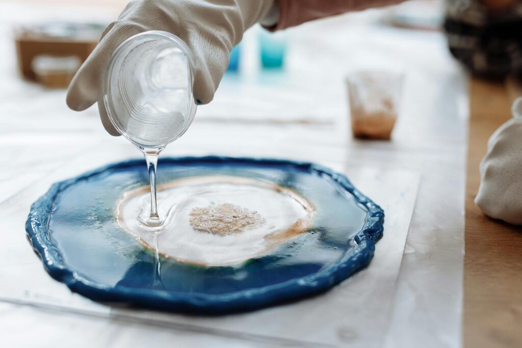 Transform Your Space with Epoxy Resin Crafts Detailed image of resin art being created with gloves and a plastic cup.