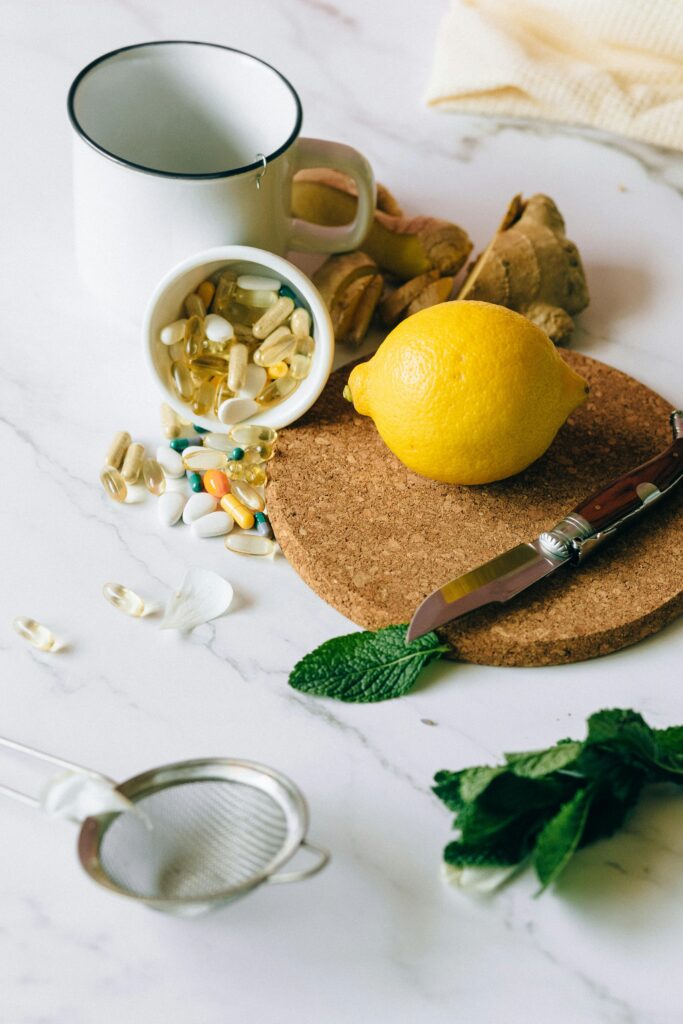 A flat lay of natural ingredients and supplements featuring lemon, ginger, and pills.