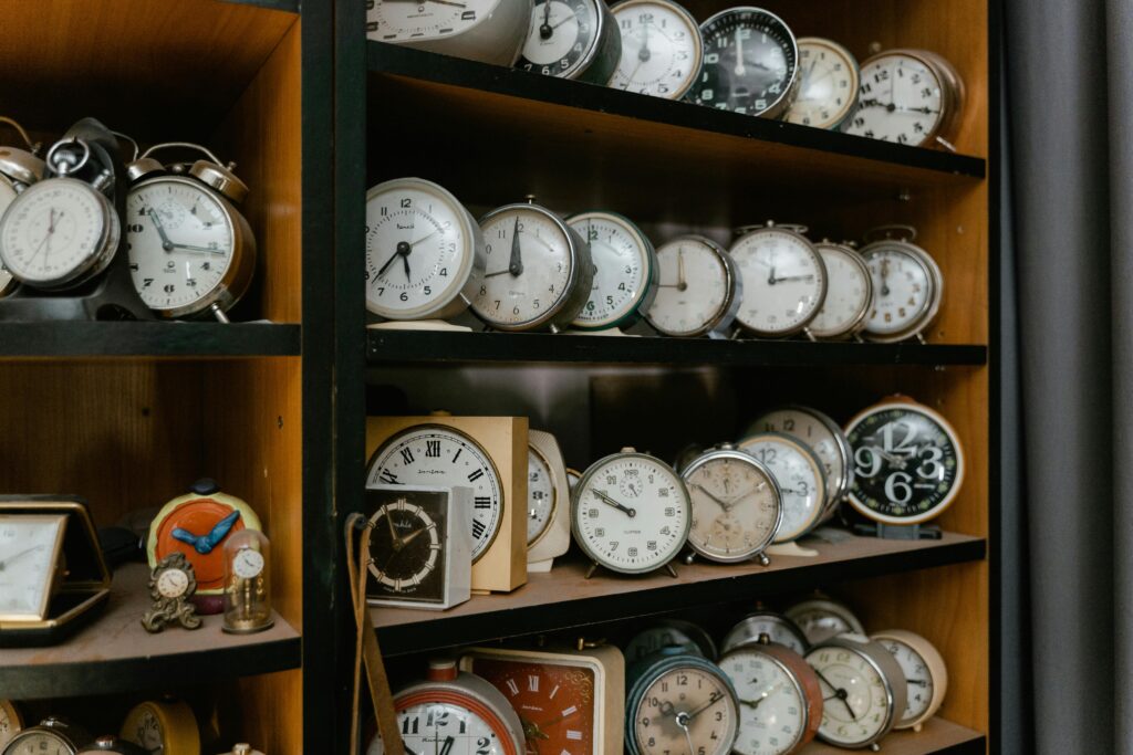 A variety of vintage alarm clocks displayed on wooden shelves, evoking nostalgia.