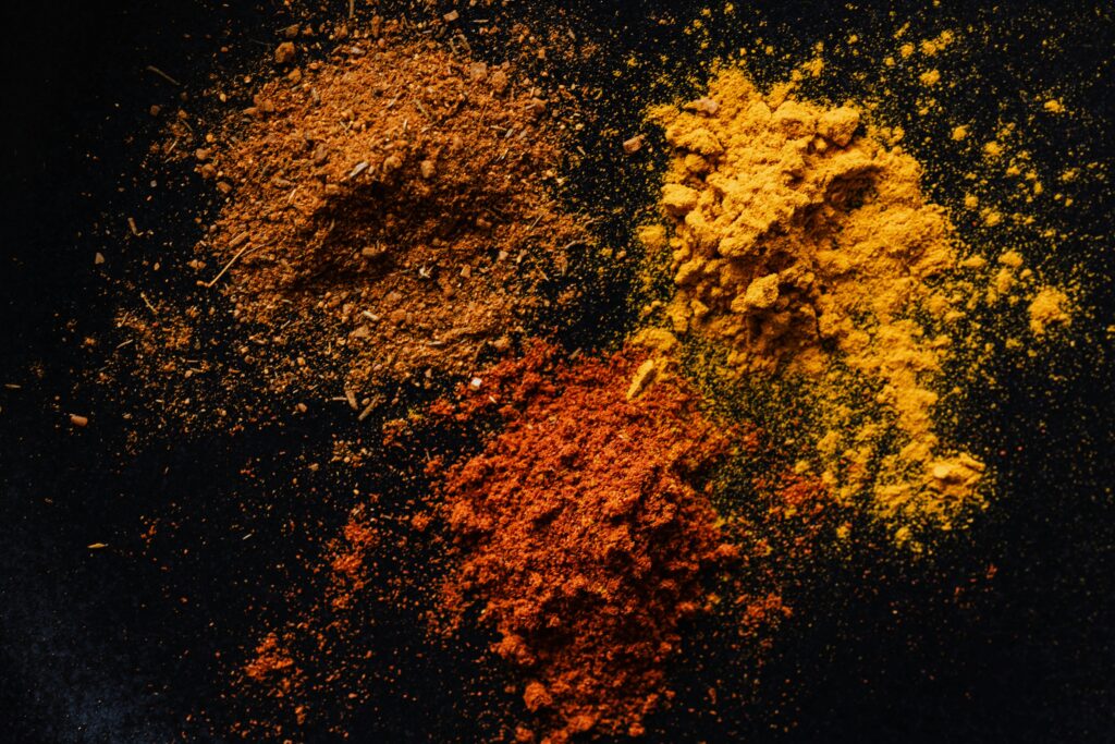 Turmeric Curcumin Capsules: Your Daily Anti-Inflammatory Essentials Vibrant assortment of spices on a black background, showcasing paprika, turmeric, and curry powders.