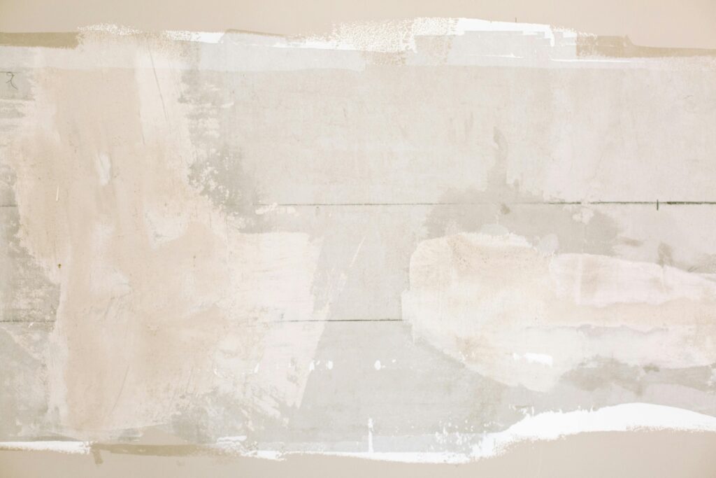 How to Repair Cracked Drywall: Simple DIY Fixes for Flawless Walls Close-up of an unfinished wall showing plaster and paint textures in a home renovation.